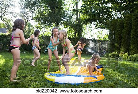 Children playing on water slide in backyard View Large Photo Image Stock Image - Children playing on water slide in backyard. Fotosearch