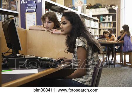 Stock Image - Children using computer in library together. Fotosearch
