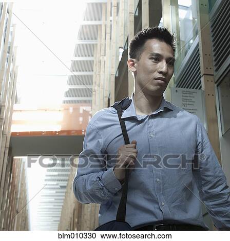 Stock Image - Chinese businessman walking on urban street. Fotosearch