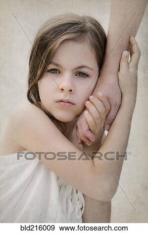 Stock Photo - Close up of anxious girl holding hand of mother. Fotosearch