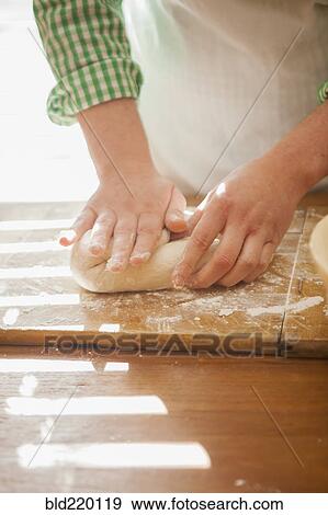 Stock Photo - Close up of baker shaping dough on counter. Fotosearch