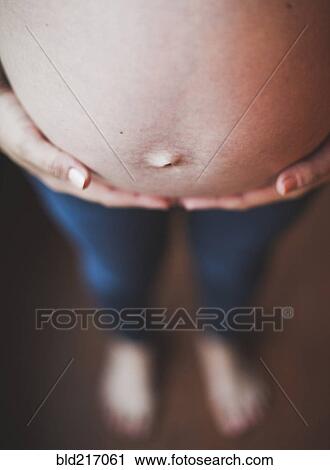 Stock Image - Close up of belly of pregnant Caucasian woman. Fotosearch
