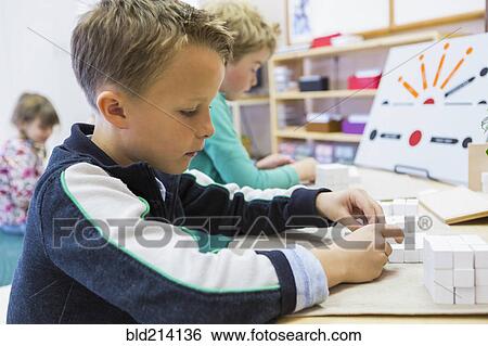 Close up of boy solving puzzle in classroom View Large Photo Image Stock Photograph - Close up of boy solving puzzle in classroom. Fotosearch