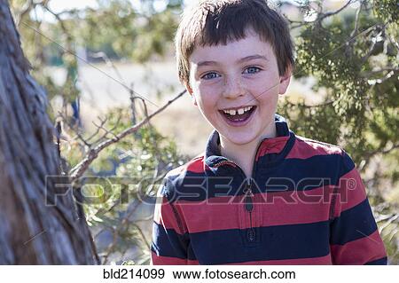 Stock Photo - Close up of Caucasian boy smiling near tree. Fotosearch
