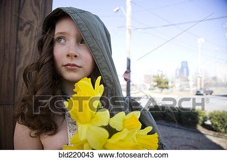 Stock Image - Close up of Caucasian girl holding flowers outdoors. Fotosearch