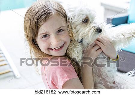 Stock Image - Close up of Caucasian girl hugging puppy. Fotosearch