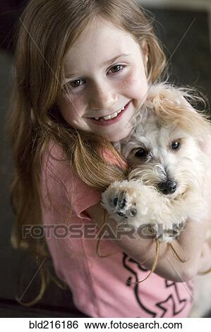 Stock Photograph - Close up of Caucasian girl hugging puppy. Fotosearch