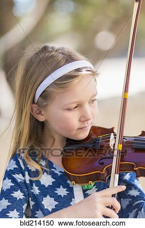 Stock Image - Close up of Caucasian girl playing violin. Fotosearch