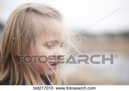 Stock Image - Close up of curious girl looking down. Fotosearch