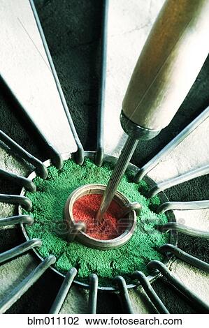 Stock Image - Close up of dart in bull's eye on dartboard. Fotosearch