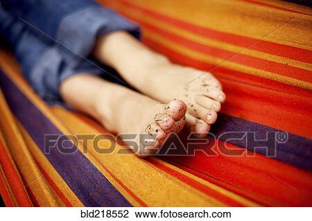 Stock Image - Close up of dirt on feet of girl on hammock. Fotosearch