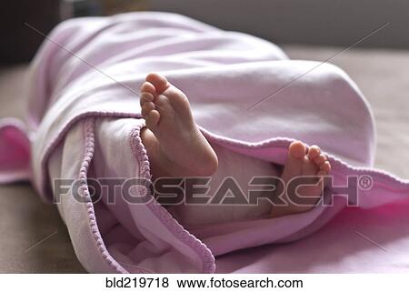 Stock Photo - Close up of feet of baby girl in blanket. Fotosearch