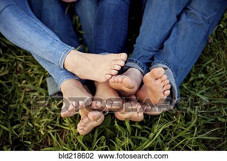 Stock Image - Close up of feet of friends in grass. Fotosearch