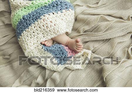 Stock Photo - Close up of feet of newborn baby wrapped in blanket. Fotosearch