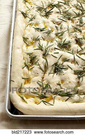 Stock Image - Close up of focaccia dough with herbs. Fotosearch