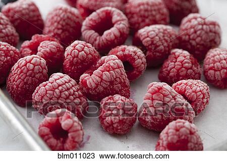 Stock Image - Close up of frozen red raspberries. Fotosearch