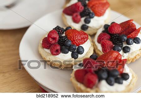 Stock Image - Close up of fruit and cream tarts. Fotosearch