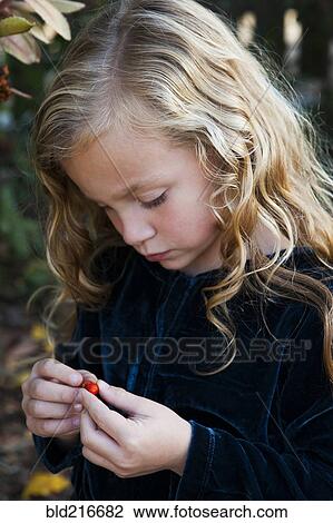 Close up of girl examining berry outdoors View Large Photo Image Stock Image - Close up of girl examining berry outdoors. Fotosearch