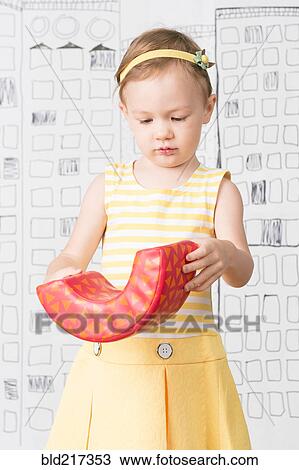 Stock Image - Close up of girl examining toy. Fotosearch