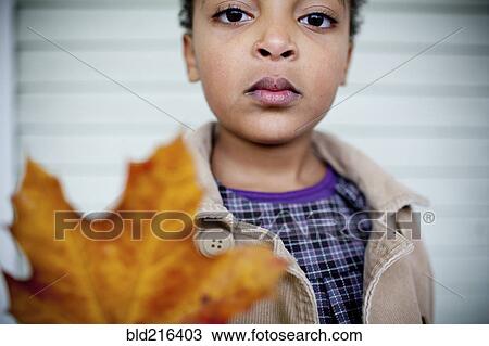 Stock Image - Close up of girl holding autumn leaf. Fotosearch
