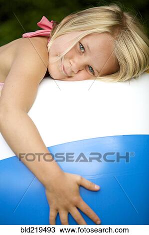Stock Image - Close up of girl hugging beach ball. Fotosearch