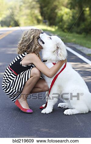 Stock Photo - Close up of girl hugging dog on road. Fotosearch