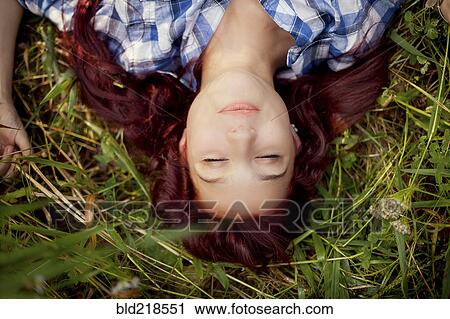 Stock Image - Close up of girl laying in grass. Fotosearch