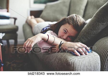Stock Image - Close up of girl laying on sofa in living room. Fotosearch