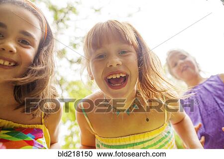 Stock Image - Close up of girls laughing outdoors. Fotosearch