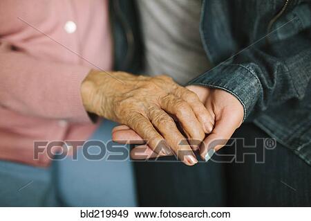 Stock Photo - Close up of grandmother and granddaughter holding hands. Fotosearch