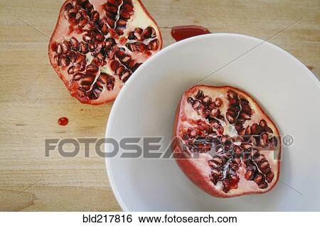 Stock Photograph - Close up of halved pomegranate on plate. Fotosearch