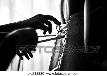 Stock Image - Close up of hands lacing corset. Fotosearch