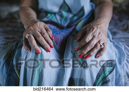 Picture - Close up of hands of older woman resting on knees. Fotosearch