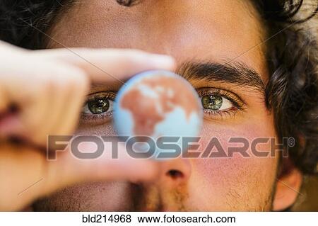Stock Photo - Close up of Hispanic man holding miniature globe. Fotosearch