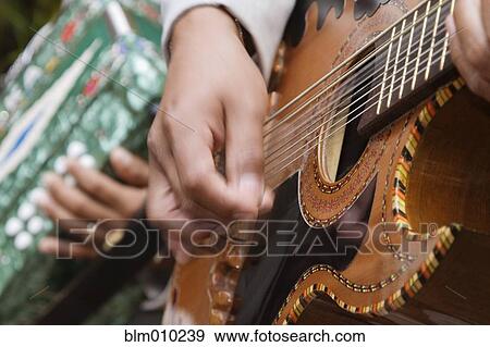 Stock Photo - Close up of Hispanic man playing guitar. Fotosearch