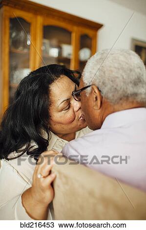 Stock Image - Close up of kissing couple in dining room. Fotosearch