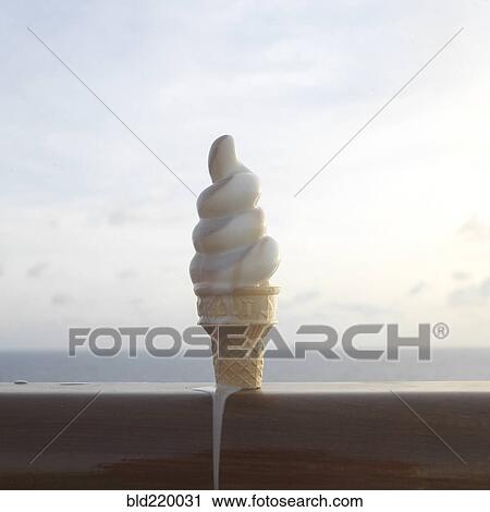 Stock Image - Close up of melting ice cream cone on banister. Fotosearch
