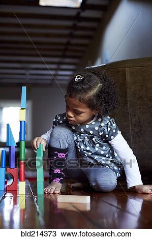 Stock Image - Close up of mixed race girl stacking wooden blocks. Fotosearch