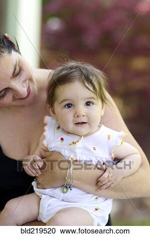 Stock Image - Close up of mother holding baby daughter. Fotosearch