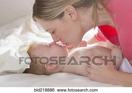 Stock Photograph - Close up of mother kissing baby girl. Fotosearch