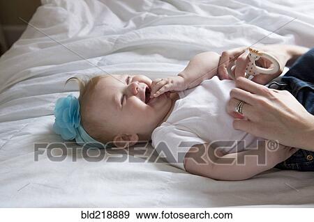Close up of mother tickling baby girl on bed View Large Photo Image Stock Photo - Close up of mother tickling baby girl on bed. Fotosearch