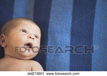 Stock Image - Close up of newborn mixed race baby laying on striped blanket. Fotosearch