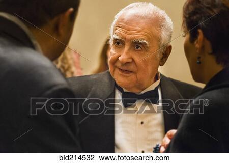 Stock Image - Close up of older man talking to friends. Fotosearch