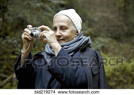 Close up of older woman photographing in forest View Large Photo Image Picture - Close up of older woman photographing in forest. Fotosearch