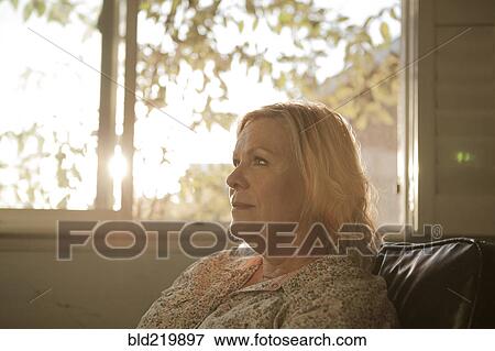 Stock Photo - Close up of older woman sitting near window. Fotosearch
