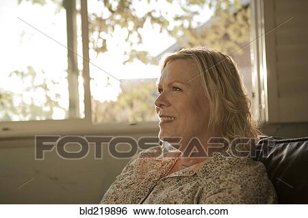Stock Photograph - Close up of older woman smiling near window. Fotosearch
