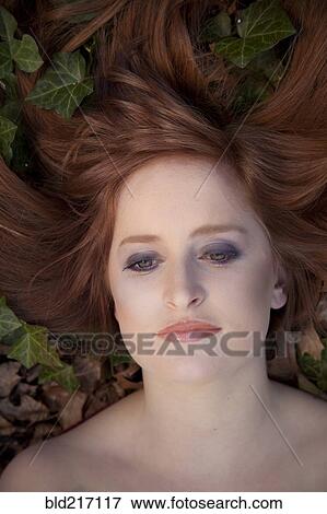Stock Photo - Close up of serious Caucasian woman laying in leaves. Fotosearch