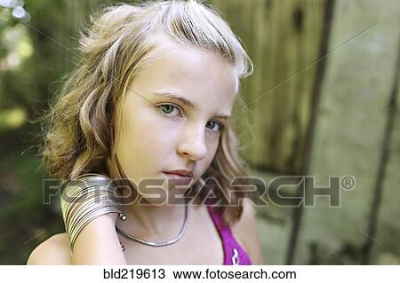 Stock Image - Close up of serious girl standing outdoors. Fotosearch