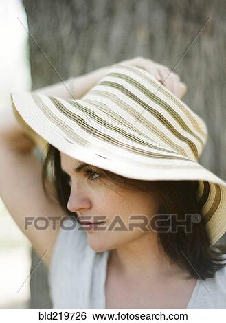 Stock Photograph - Close up of serious woman wearing sun hat. Fotosearch