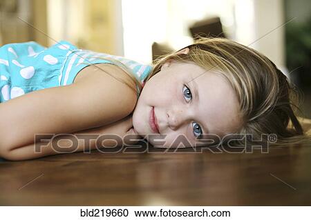 Stock Image - Close up of smiling girl laying on floor. Fotosearch